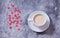 Heart-shaped red candy and a cup of coffee on a concrete background. Top view. Copy space