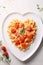 Heart shaped spaghetti with tomato sauce and parmesan cheeses on white plate. AI Generated