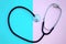 Heart shaped stethoscope, on a pink and blue background.