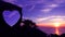 Heart-shaped stone on a mountain with purple sky sunset.