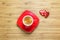 Heart shaped sweets wrapped in a bright red foil lying on a wooden texture with red cup of coffe near it.