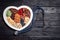 Heart shaped tray with nuts and dried fruits near stethoscope on wooden background