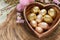 Heart shaped wooden bowl holds golden painted Easter eggs, festive decor
