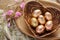 Heart shaped wooden bowl holds golden painted Easter eggs, festive decor