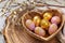 Heart shaped wooden bowl holds golden painted Easter eggs, festive decor