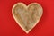 Heart shaped wooden bowl on a red background, rustic happy Valentineâ€™s Day