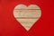 Heart shaped wooden hole torn through paper,  on red background. Top view with space for your greetings