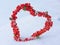 Heart-shaped wreath of red berries in the snow as a greeting for