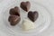 Heart shapped chocolate sweets, brown and white color, transparent retro plate with pralines