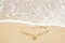 Heart sign on beach. Heart symbol on sandy beach and sea waves with foam. Love and hello summer concept. Vacation, relax and