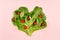 Heart of spring healthy food - cherry tomatoes and leaves spinach on pink background. Valentine`s day backdrop.