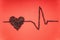 Heart symbol and a heart rate line made of roasted coffee beans arranged on a red background. Caffeine and heart health concept
