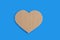 Heart symbol made of brown cardboard with jagged edges on blue background