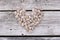 Heart symbol made of nuts on wooden table. Apricot nuts white background.