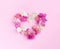 Heart symbol made of white, pink flovers bougainvillea and leaves on pink background.