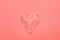 Heart symbol in trendy living coral color made from pink Himalaya salt crystals on monochrome background. Valentine