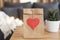 Heart Tag Paper Bag On The Coffee Table. Sofa In The Background. Valentine Day Favor Bag. Red Heart Mock Up. Valentines Day