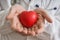 Heart transplantation concept. Doctor holds red heart model in hands