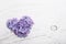 Heart of violet or blue lilac blossom on white shabby wooden