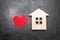 Heart and wooden house on a gray concrete background. The concept of a love nest, the search for new affordable housing for young