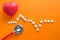 Heartbeat pulse line of colorful pills on orange background
