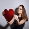Heartbreaker. Temptress. Seductive woman. Portrait of amazing young fashion woman posing at studio with red heart. Love. Valentine