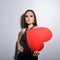 Heartbreaker. Temptress. Seductive woman. Portrait of amazing young fashion woman posing at studio with red heart. Love. Valentine