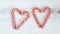 Hearts made from striped red-white lollipops on a white wooden background