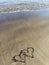 Hearts painted on the beach with water