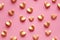 A heartwarming pattern of 3D golden hearts on a pastel pink background, perfect for themes of love, Valentine's Day