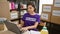 Heartwarming portrait of serious young beautiful hispanic female volunteer with short hair, sitting indoors at charity center