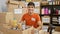 Heartwarming portrait of a young, handsome hispanic man, smiling confidently while volunteering at a charity center, sitting at a