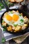 Hearty breakfast. Hash brown potatoes, chicken, onion, parsley, oregano and a fried egg in a frying pan on the old wooden