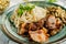 A hearty meal on the table, spaghetti with fried pork chunks, green canned peas and watercress grass. Next to the sauce