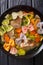 Hearty meat soup, with colored farfalle pasta and vegetables close-up. Vertical top view