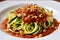 hearty plate of zucchini pasta with red sauce and pine nuts