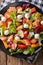 Hearty salad with salmon, mozzarella and fresh vegetables close-up on a plate. Vertical top view