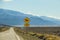 A heat shimmer on the road and cars in the high desert with mountains in the distance and a sign with a horse that says Open Range