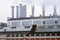 Heat station in the city. Smoking pipes against blue sky. Aluminum pipes of old Industrial building of factory