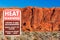 Heat warning sign informs travelers of the dangers of heat exhaustion from hiking in the desert climate. Blurred scenic red