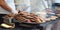 Heated metal tray full of meat specialties from the Serbian and Balkans cuisine. In the background  bread, meat on the grill and c