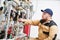 Heating engineer or plumber inspector in boiler room taking readouts or adjusting meter