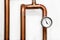Heating system`s cooper pipes with Thermometer on a white wall