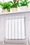 Heating white radiator radiator with flower and window.