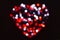 Heavily blurred red, white and gray circles of light in the shape of a heart with bokeh effect on a black background