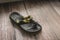 A heavily damaged flip flop on the floor. Torn and chewed up by a dog