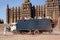 A heavily-laden truck with passengers on the roof pulls away from the Great Mosque in Djenne, Mali