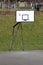 Heavily used old dilapidated basketball hoop mounted on strong partially rusted metal frame on edge of paved playground