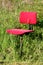 Heavily used old office chair with dilapidated red fabric mounted on rusted metal pole left in family house backyard