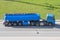Heavy big fuel tanker with blue lame tank driving on city highway, side aerial view